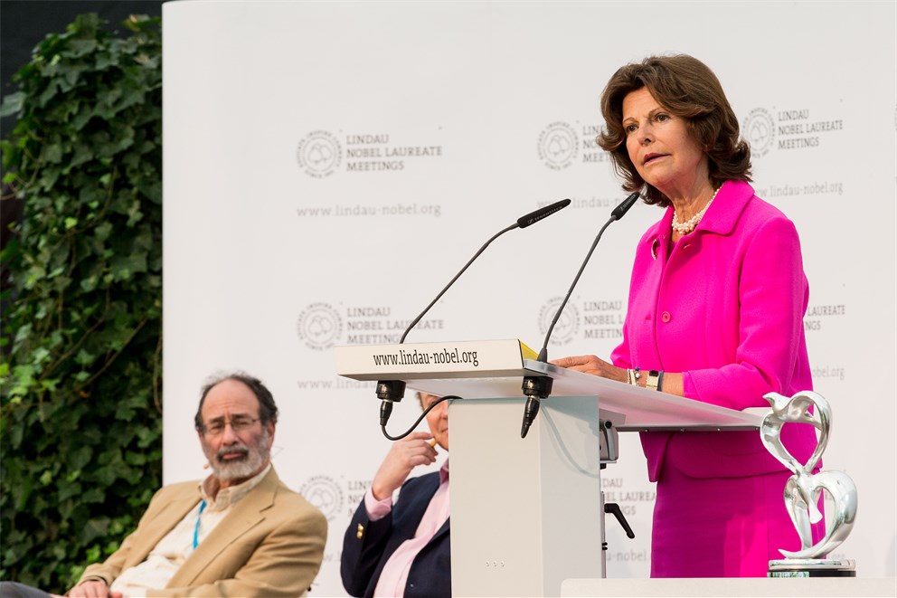 Queen Silvia of Sweden	delivering her welcome address at the closing panel discussion of the 5th Meeting on Economic Sciences on Mainau Island.